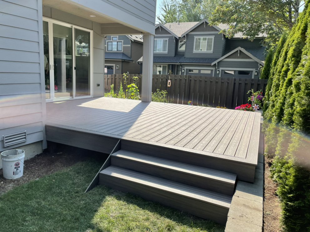 Finished gray deck with wide steps beside a house, showing the materials and features that affect deck cost in Seattle