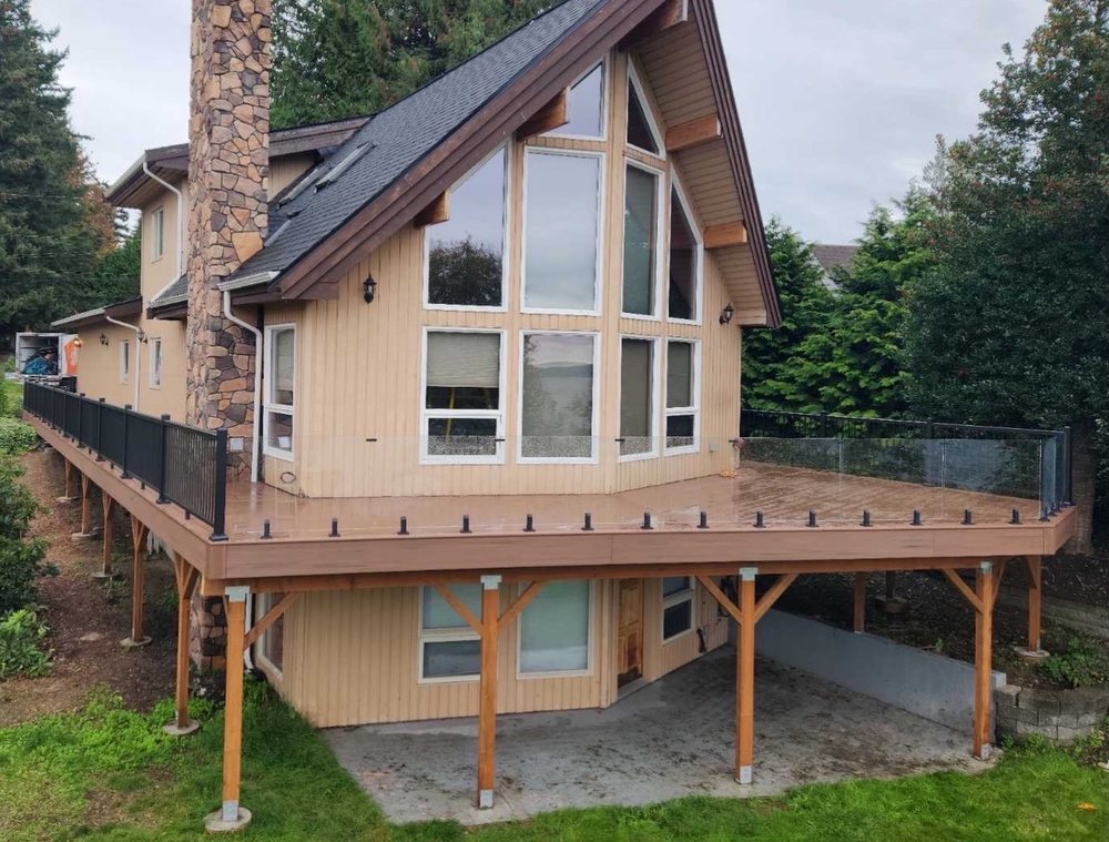 Raised wraparound deck supported on timber posts beside a house, illustrating projects that need a Seattle deck permit